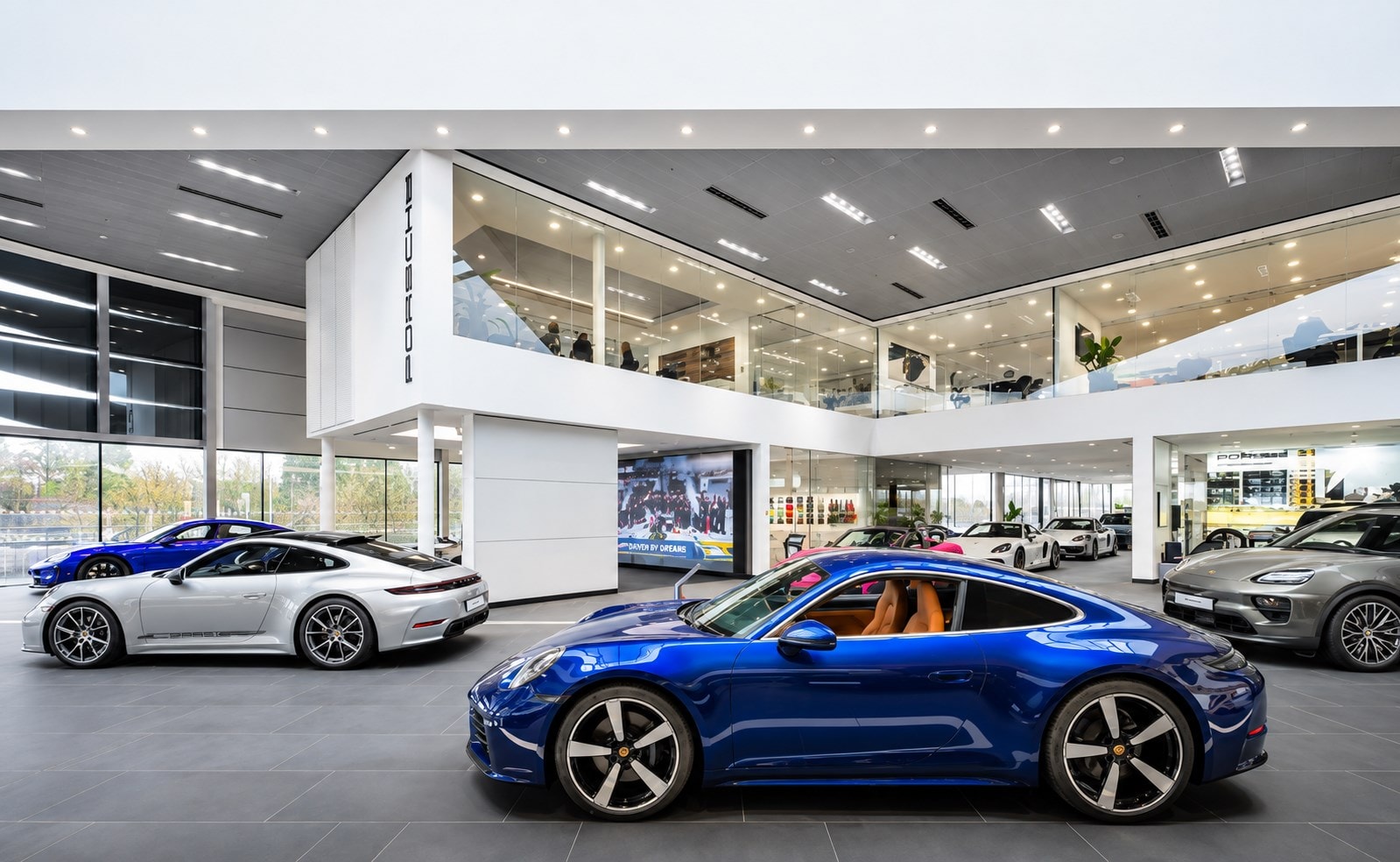 Sports cars in a bright, double-height showroom.